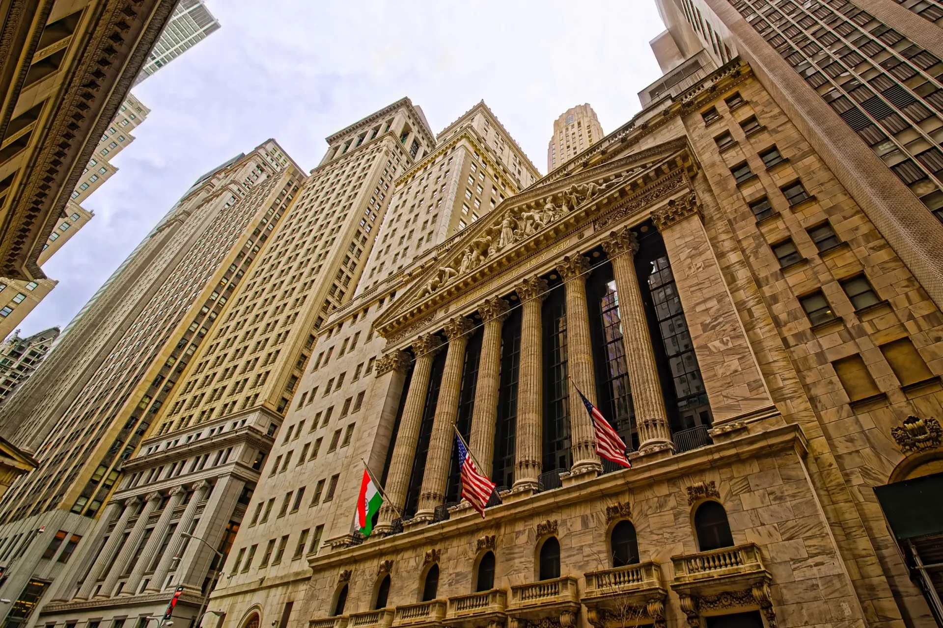 New York Stock Exchanges søjlefacade med det amerikanske flag, set nedefra fra Broad Street