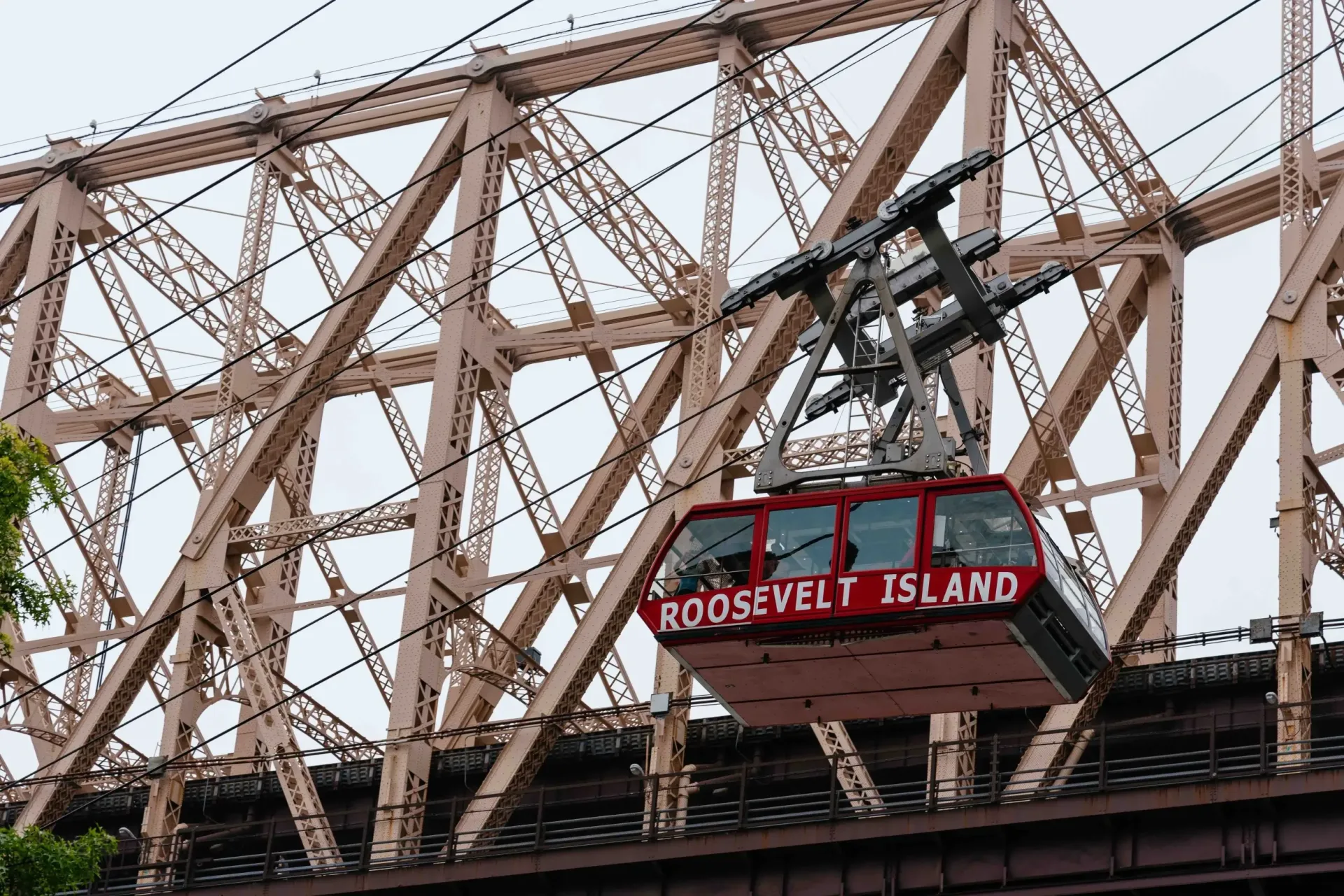Den røde kabine fra Roosevelt Island Tramway på vej over East River langs Queensboro Bridge